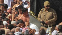 Seorang polisi menjaga para jamaah berebut mencium Hajar Aswad yang berbingkai logam di sebelah kanan sang polisi. Hajar Aswad adalah batu yang dipercaya turun dari surga (Fitraya/detikTravel)
