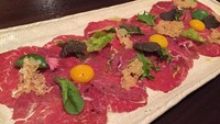Suguhan menu pembuka lainnya berupa Carpaccio di Wagyu. Lembaran tipis wagyu mentah diberi topping kunng telur puyuh, black truffle, herba dan parmesan chips.