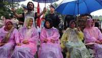 Di bawah guyuran hujan, massa tetap beraksi.