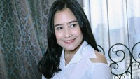 Ia tampak mengenakan kemeja putih dengan potongan di bagian bahu.