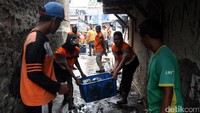 Petugas mengangkut sampah ke truk.