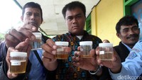 Para karyawan memperlihatkan urinenya sebelum dicek.