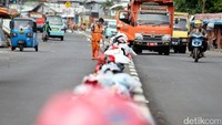 Tampak sebuah mobil truk sampah yang siap mengambil tumpukan sampah di pembatas jalan tersebut.