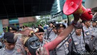 Perwakilan aksi berorasi di depan barikade polisi. 