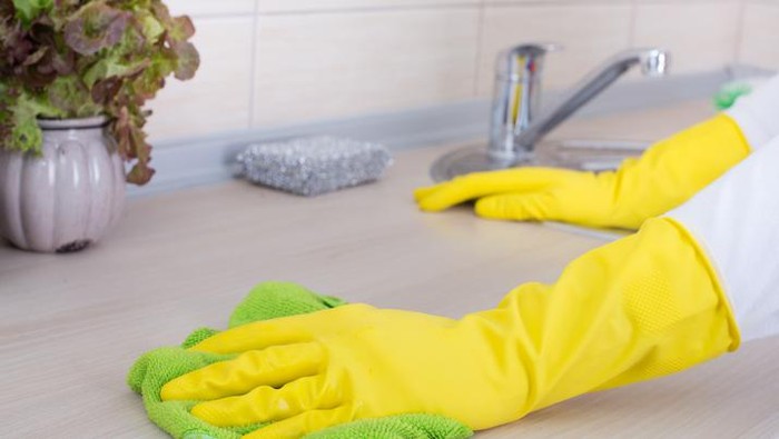 Young couple cleaning kitchen together. Focus is on smiling woman.