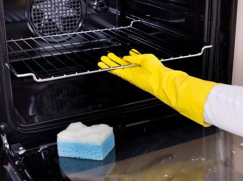 Young couple cleaning kitchen together. Focus is on smiling woman.