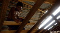 Pekerja tengah memotong kayu untuk lantai atas kapal.
