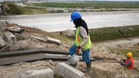 Pekerja membuat saluran air di pinggir jalan tol.