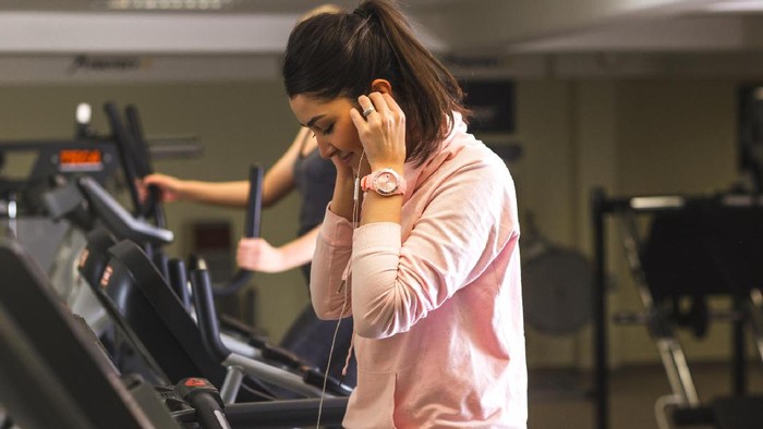 treadmill MP pasang musik Girl running on the treadmill and listening music at the gym.