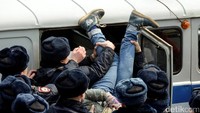 Seorang demostran dimasukan ke dalam mobil. REUTERS/Maxim Shemetov.