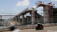Pengendara motor melintas diantara peroyek LRT di kawasan Cibubur.