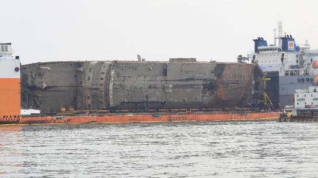 Bangkai kapal Sewol setelah diangkat dari dasar laut dan disiagakan di antara dua kapal semi-selam pada 26 Maret