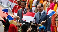 Anak-anak yang mengenakan pakaian adat mengibarkan bendera Indonesia dan Prancis untuk menyambut kedatangan Presiden Hollande. Pool/Darren Whiteside/Reuters/detikFoto.