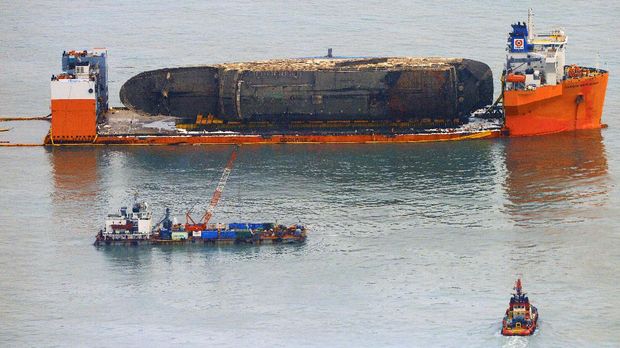 Bangkai kapal Sewol setelah diangkat dari dasar laut dan disiagakan di antara dua kapal semi-selam pada 26 Maret