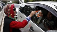 Seorang relawan membagikan stiker kepada pengendara mobil.