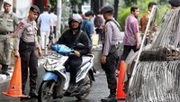 Pengendara sepeda motor melintas dengan penjagaan aparat kepolisian.