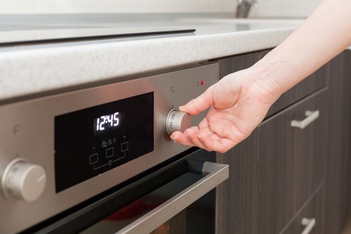 Close Up Of Hand Setting Temperature Control On Oven