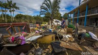 Warga berjalan di antara barang-barang yang hancur akibat badai. Glenn Hunt/Getty Images.