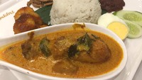 Nasi lemak tersaji dengan aneka lauk. Ada kari ayam, sambal goreng udang, irisan telur rebus, teri dan kacang goreng.