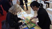 Petugas booth Indonesia sedang mempromosikan sebuah karya ilustrasi anak bangsa kepada seorang pengunjung.