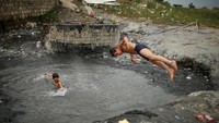 Foto: Mereka terlihat tanpa beban meloncat ke dalam kolam ini. Meski terlihat kotor, tetapi kolam lumpur ini mengandung belerang yang baik untuk kesehatan kulit (Suhaib Salem/Reuters)