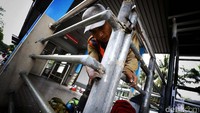 Pekerja mengamplas tiang-tiang halte sebelum dicat.