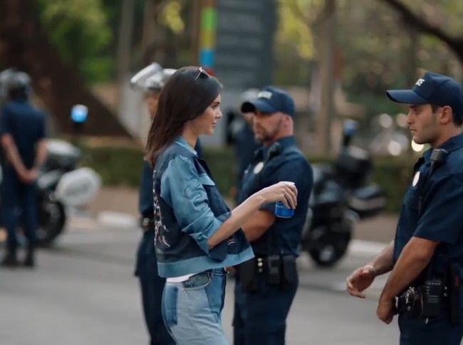 Pepsi menarik iklan video yang dibintangi Kendall Jenner setelah banyaknya protes dari netizen. Iklan menampilkan Kendall Jenner mencoba meredakan protes dengan memberikan polisi sekaleng Pepsi. Netizen menilai iklan itu salah dan buruk untuk ditayangkan. Foto: Youtube