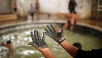 Foto: Lumpur mengandung belerang ini biasanya dibalurkan ke seluruh tubuh. Kemudian ditunggu sampai kering, baru bisa dibilas kemudian berendam kembali ramai-ramai ke kolam berair panas (Suhaib Salem/Reuters)