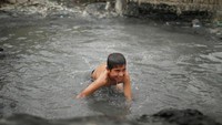 Foto: Tak hanya orang dewasa, anak-anak juga senang sekali berendam di kolam lumpur yang terletak di luar ruangan. Bermain air seperti ini, sedikit mengobati duka mereka akibat perang yang tak henti di Irak (Suhaib Salem/Reuters)