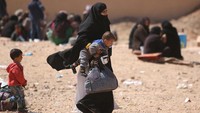 Seorang wanita dengan menggendong anaknya tiba di pengungsian di Desa al-Mahmudli. Ia keluar dari kotanya, Raqqa yang dikuasai ISIS. REUTERS/Rodi Said.