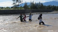 Warga Timor Leste menantang arus deras Sungai Malibaka di Turiskain, Kecamatan Raihat, Kab Belu. Mereka menyeberang ke Indonesia untuk pergi ke pasar (Fitraya/detikTravel)