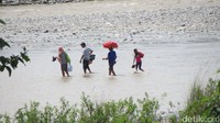 Warga Timor Leste yang pulang dari berbelanja di pasar perbatasan. Mereka kembali harus menempuh bahaya menyeberang Sungai Malibaka selebar 100 meter yang sebagian cukup dalam sampai sepinggang (Fitraya/detikTravel)