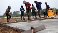 Para pekerja melakukan pembetonan jalan.