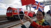 Seorang warga melepas keberangkatan kereta dengan mengibarkan bendera Inggris dan China. Peter Nicholls/Reuters.