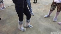 Para penonton pun menyiapkan plastik pelindung sepatu serta jas hujan.