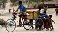 Terlihat seorang anak tengah mengenendarai sepeda berisikan kotak es krim yang langsung diikuti oleh beberapa anak-anak. REUTERS/Mohammad Ponir Hossain.