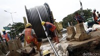Pekerja menarik gulungan kabel 150 kV untuk dipasang di dalam tanah.