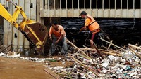 Sejumlah petugas membersihkan hamparan sampah yang menumpuk di Pintu Air Manggarai, Jakarta, Jumat (14/04/2017).