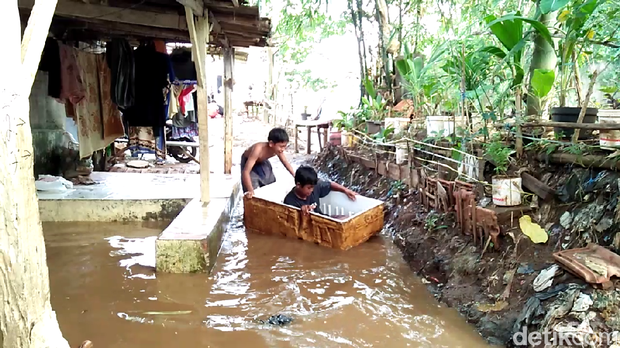 Anak-anak Asyik Bermain Perahu di Tengah Banjir Tebet