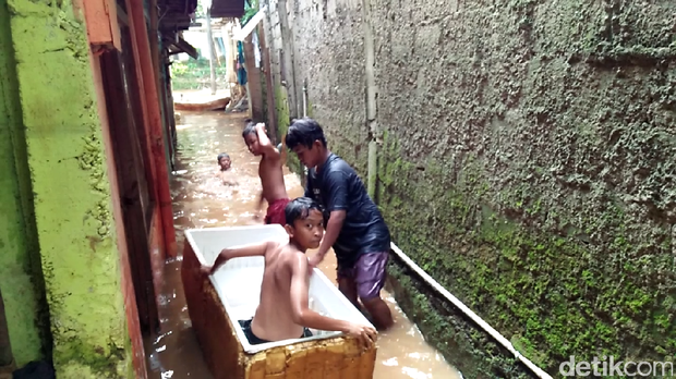 Anak-anak Asyik Bermain Perahu di Tengah Banjir Tebet