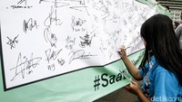 Seorang warga tengah membubuhkan tanda tangan dibentangan spanduk panjang saat digelarnya hari bebas kendaraan bermotor, Jakarta, Minggu (16/4/2017).