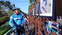 Seorang pengendara sepeda nampak antusias saat melihat pameran foto. Pool/Febry Angga Palguna.