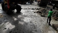 Seorang pekerja membersihkan tumpukan sampah sisa akitifitas jual beli.