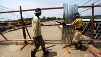 Akses ditutup, para petugas tengah menutup jembatan dengan pagar kayu dan seng.