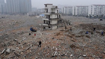 Proyek tetap berjalan, pembangunan jalan tetap dikerjakan meskipun masih ada bangunan yang ngeyel bertahan tetap berdiri kokoh di tengah ruas jalan yang akan dibangun. Foto: Reuters
