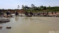 Warga menyeberangi Sungai Cipamingkis lewat jembatan darurat.