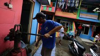 Seorang warga menimba air di kampung yang telah dicat aneka warna.
