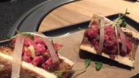 Steak Tartare berupa wagyu mentah cincang yang disajikan di atas sumsum tulang bakar. Topping pine nut menyempurnakan sajian gurih ini.