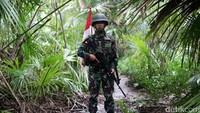 Seorang anggota Yonif Raider 641/Beruang berpatroli di tengah hujan.
