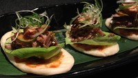 Steamed bun berupa roti hangat bertopping daging bebek BBQ dan foie gras.